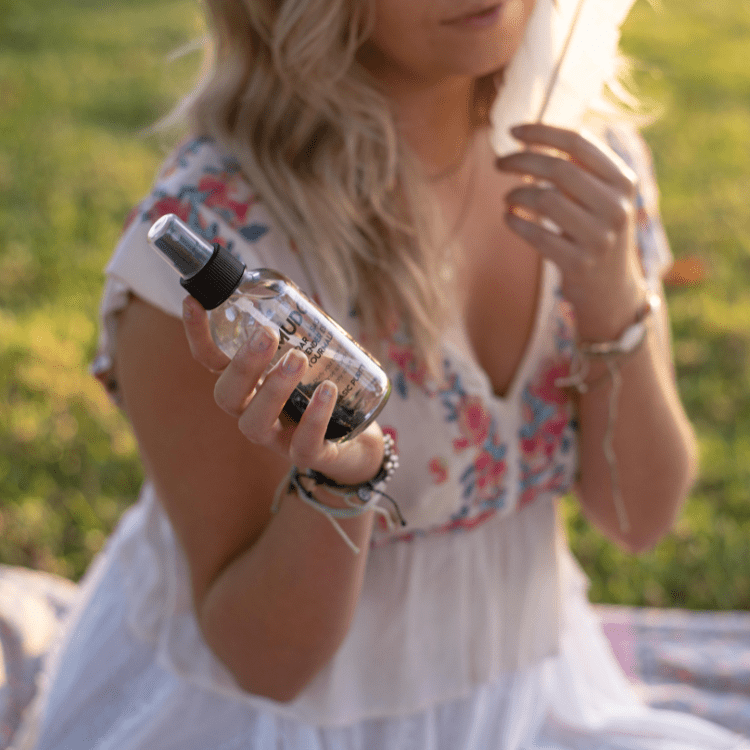 A woman holding the smudge spray.